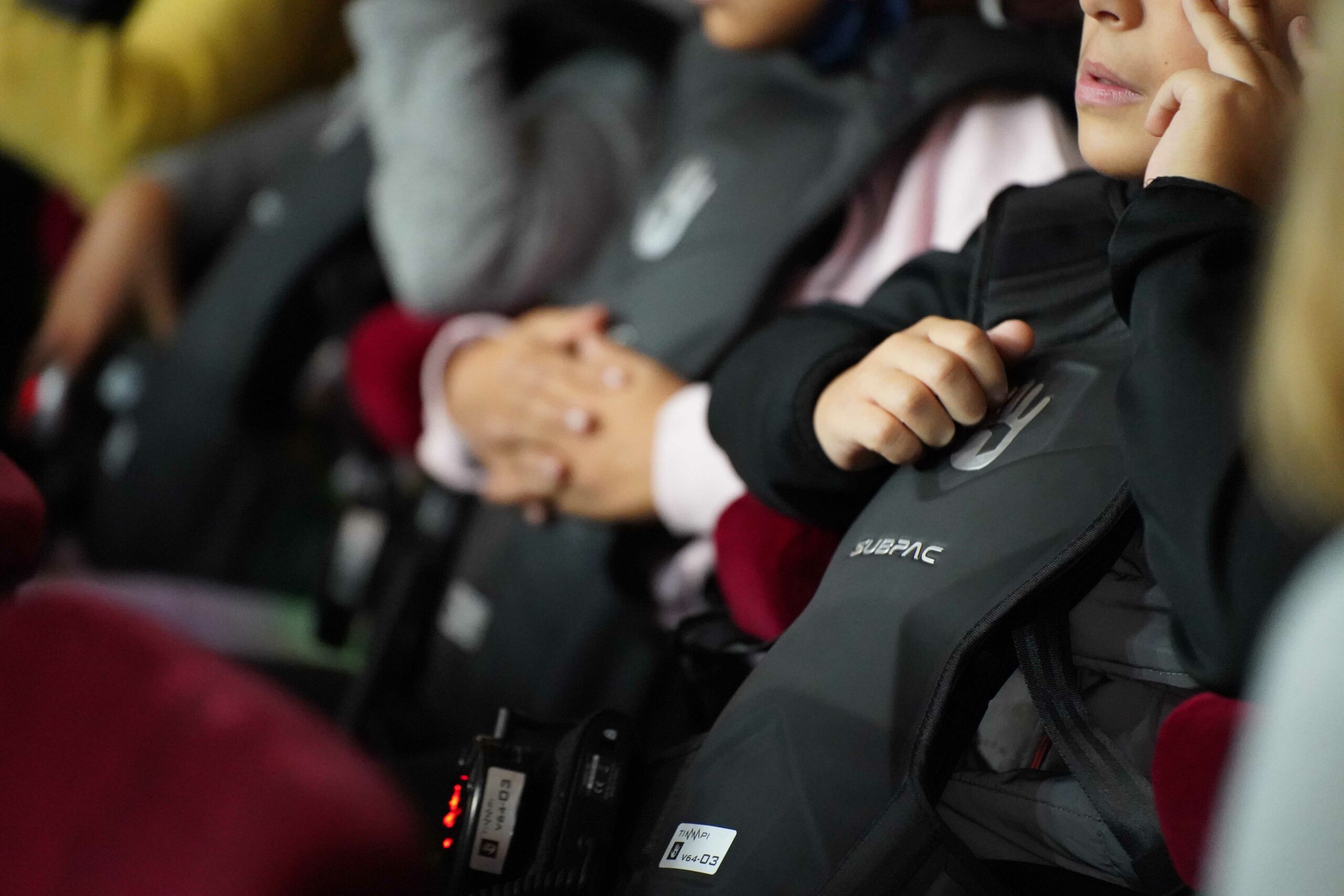 Un enfant sourd équipé d'un gilet vibrant subpac lors d'un concert chansigné